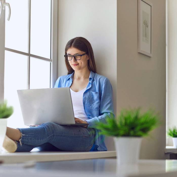 Woman sitting in the window with a laptop on her lap